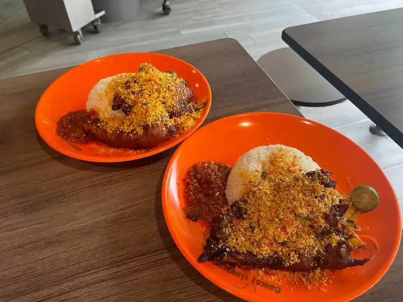 Two plates of ayam berempah on the hawker table at the stall